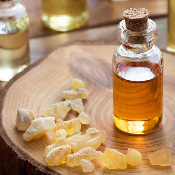 Frankincense resin and a small glass bottle of frankincense oil on a wooden surface – Wildkinn non-toxic skincare.